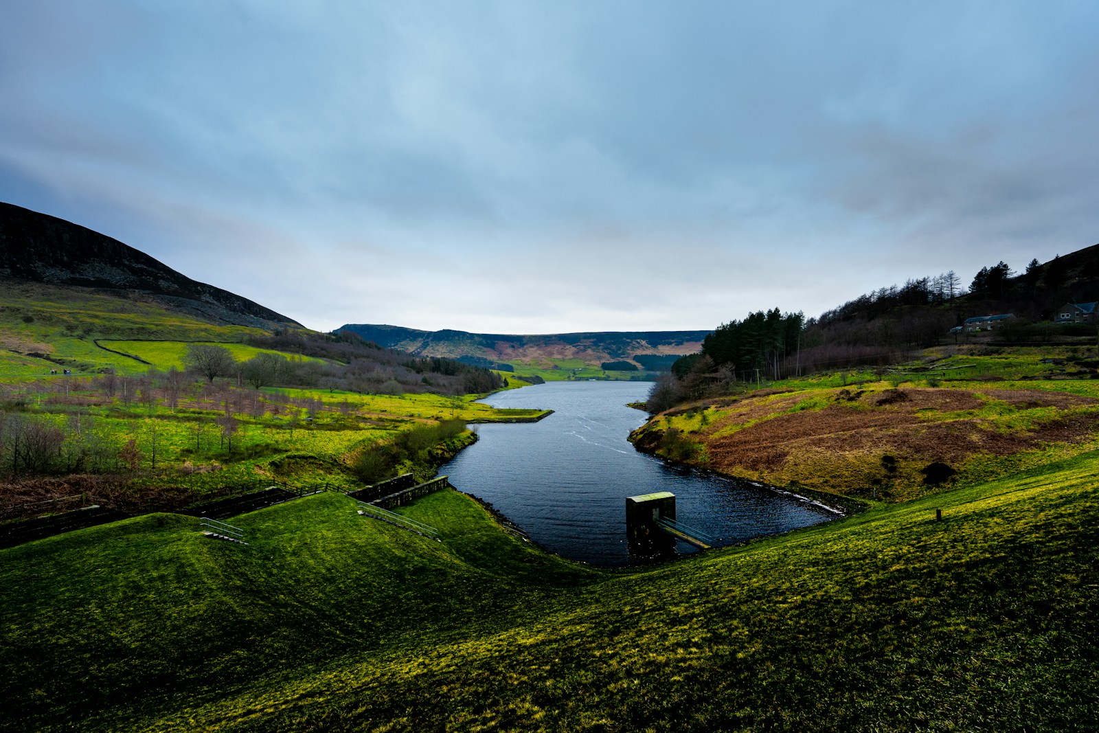 a body of water surrounded by a lush green hillside